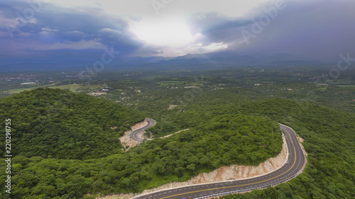 Aerial shot of Mexican landscape with sunset, green wooded areas and road