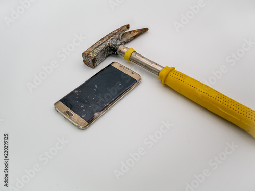 damaged smartphone disply with hammer and white background photo