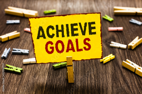 Handwriting text writing Achieve Goals. Concept meaning Results oriented Reach Target Effective Planning Succeed Clothespin holding yellow paper note several clothespins wooden floor