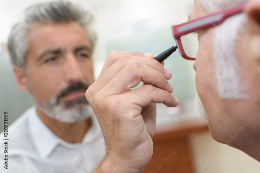 optician using and ophthalmoscope to look into a patients eyes optician using and ophthalmoscope to look into a patients eyes