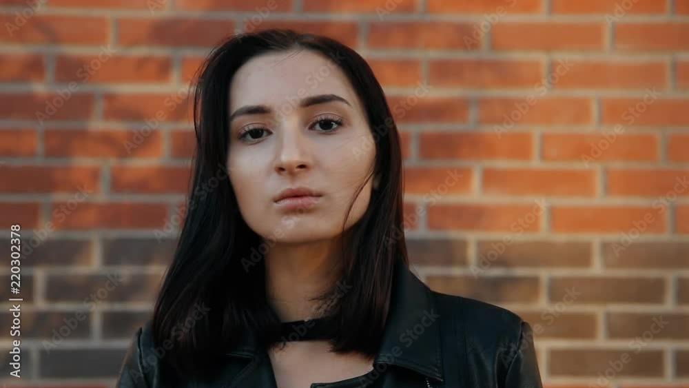 Portrait of a young serious sexy woman against a brick wall. Slow motion shot. Portrait of a young serious sexy woman against a brick wall. Slow motion shot.