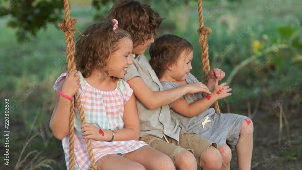 Large family. Adopted children. The younger sister resorts to her elder brother and sister to ride on a swing. Happy family, love between brothers and sisters, love of younger children Large family. Adopted children. The younger sister resorts to her elder brother and sister to ride on a swing. Happy family, love between brothers and sisters, love of younger children