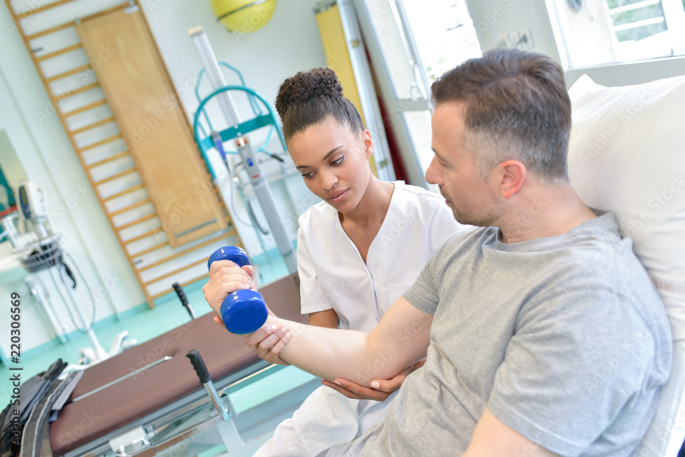 nurse helping patient to exercise with dumbbels nurse helping patient to exercise with dumbbels