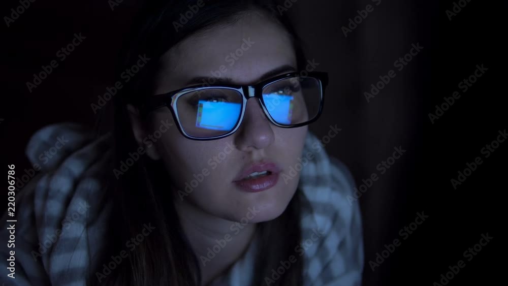 A young girl in glasses works for a laptop outside of working hours. Girl In A Dark Room, Surf The Internet Using A Laptop, Extreme Close-Up Eye A young girl in glasses works for a laptop outside of working hours. Girl In A Dark Room, Surf The Internet Using A Laptop, Extreme Close-Up Eye