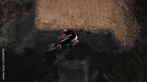 Extreme sports athlete doing tricks in slow motion on a big BMX dirt jump with his bicycle photo