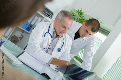mature male doctor with assistant analyzing x-ray test