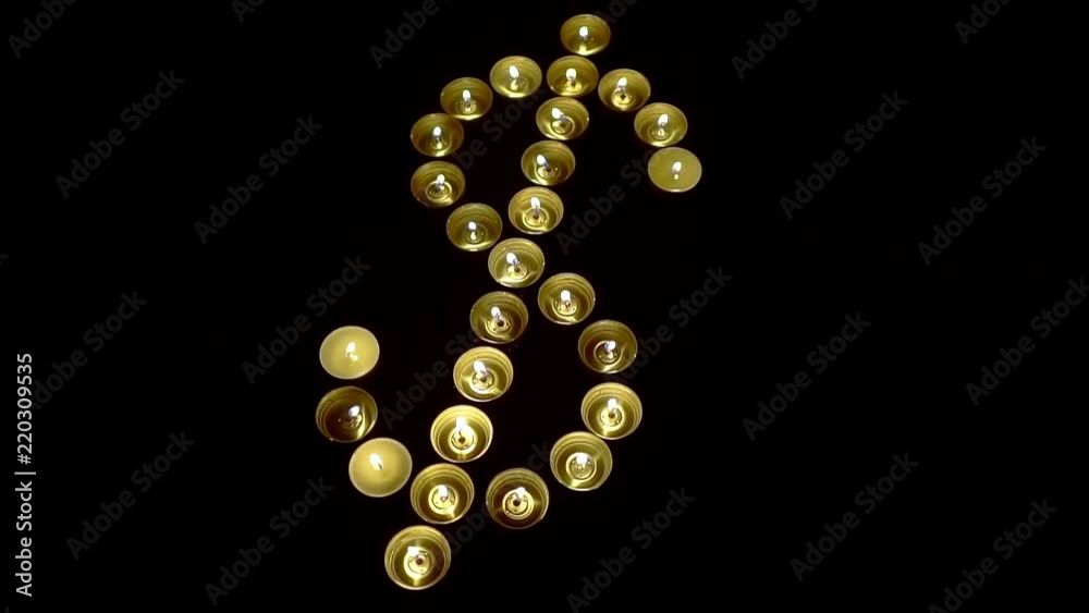 small decorative candles are standing in shape of dollar in black table in night small decorative candles are standing in shape of dollar in black table in night