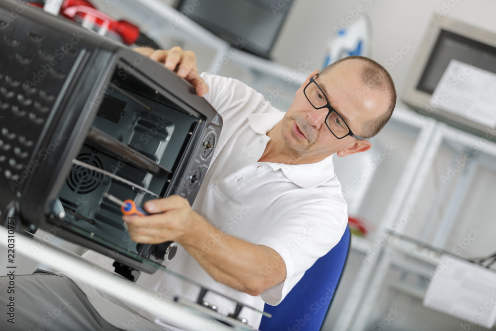 repairman working on a microwave in the kitchen repairman working on a microwave in the kitchen