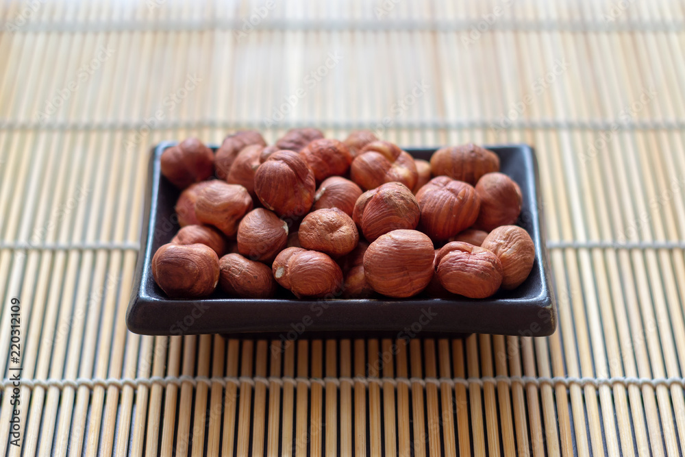 Obraz premium Hazelnut in a plate on a bamboo Mat