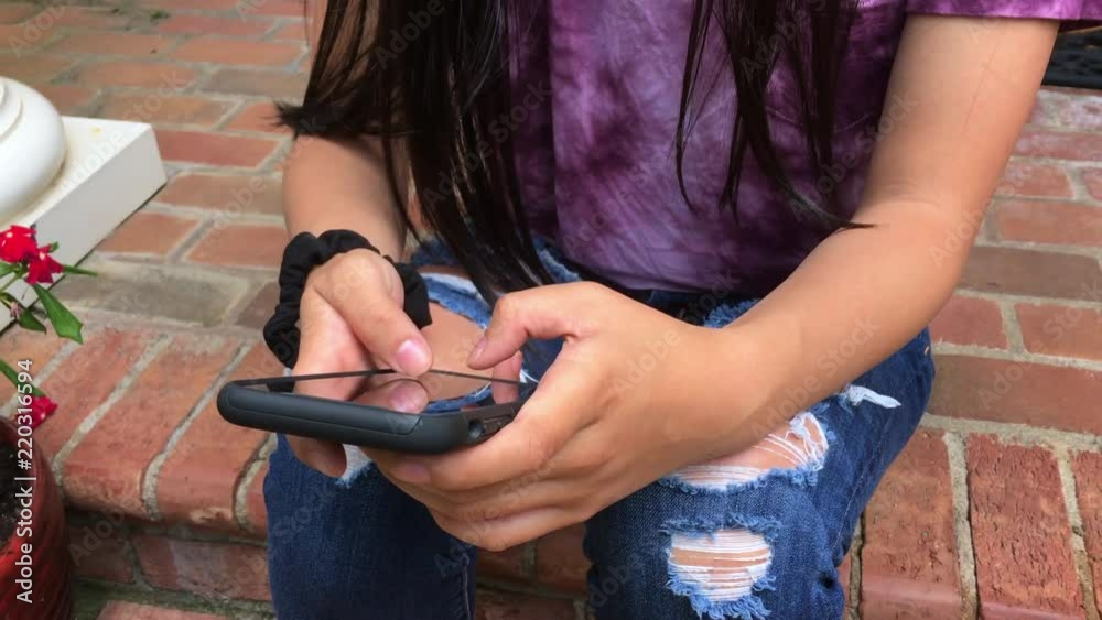 Teen girl texting on the front steps