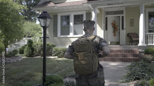 Soldier walking up to house in slow motion