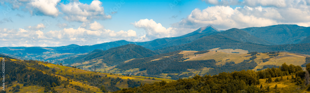 beautiful hilly countryside in autumn. beautiful weather with clouds on a blue sky above the distant mountain ridge with high peak. creative color toning applied