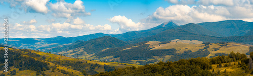 beautiful hilly countryside in autumn. beautiful weather with clouds on a blue sky above the distant mountain ridge with high peak. creative color toning applied