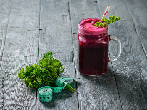 Fresh beetroot smoothie, measuting tape, two beet and parsley on black wooden table. The concept of dietary natural food. Vegetarian cuisine. The view from the top. photo