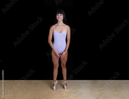 Ballerina is smiling and is wearing a lilac leotard on a black background