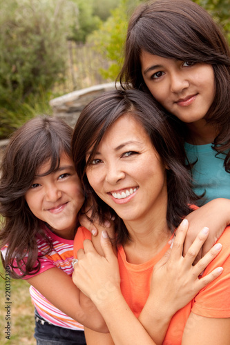 Asian mother and her daughters hugging and laughing.