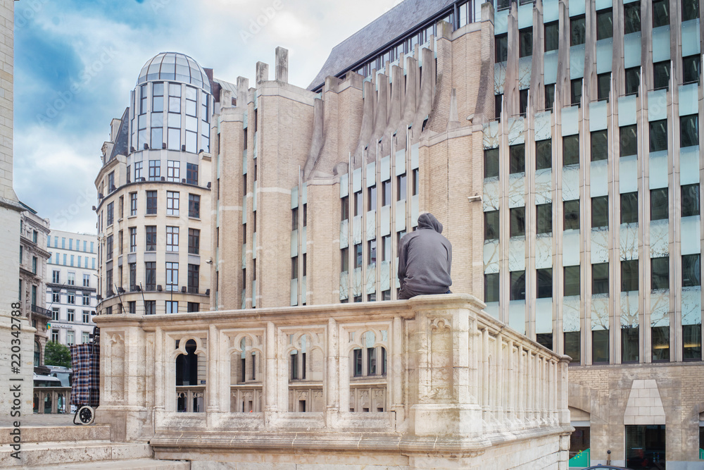 Man sitting on a stony enclosure surrounded by the architecture of the city