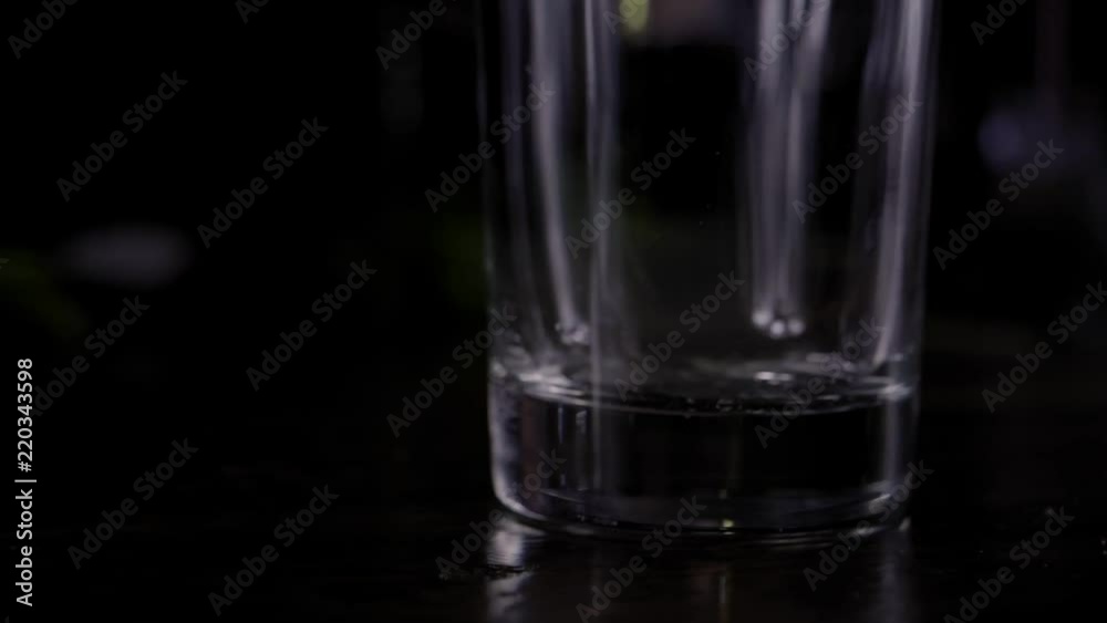 Making a Mojito cocktail; Close-up of raw sugar cubes falling into a highball glass; on black; pan around. Making a Mojito cocktail; Close-up of raw sugar cubes falling into a highball glass; on black; pan around.