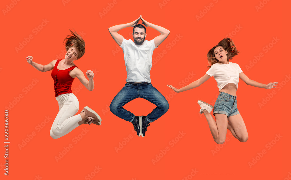 Freedom in moving. Mid-air shot of pretty happy young man and women jumping and gesturing against orange studio background. Runnin girl in motion or movement. Human emotions and facial expressions