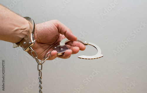 A man's hand holds handcuffs. photo