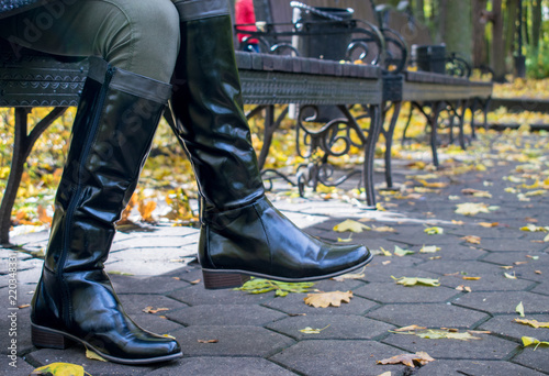 Female legs in black boots in the autumn.
