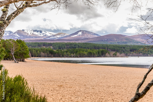 Sandy beach and beautiful mountains around Loch Morlich in the Highlands of Scotland