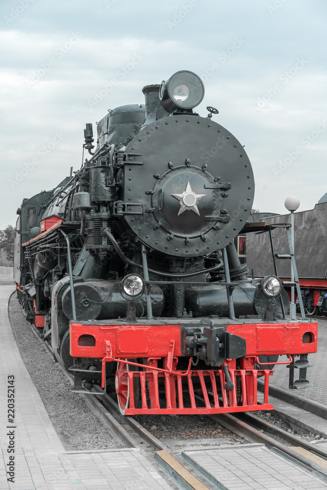 Black vintage steam locomotive with red wheels on the railway.