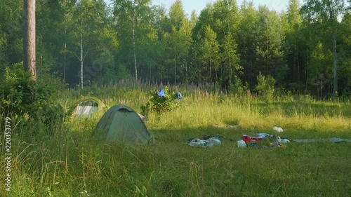 Tents and tourists' belongings on glade in forest photo