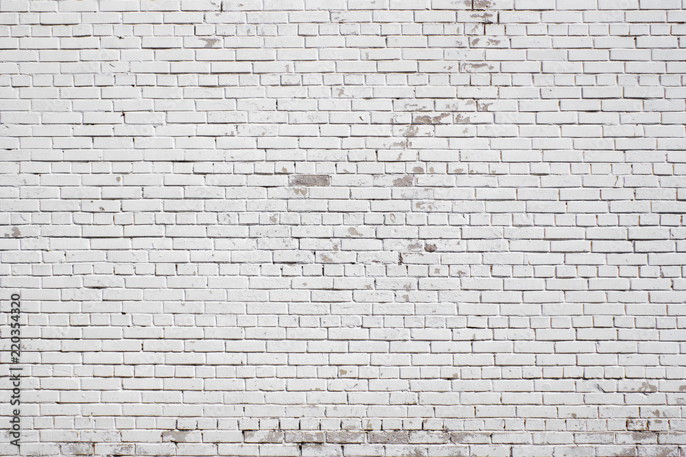 Wall from a white brick with a regular laying with scratched surface