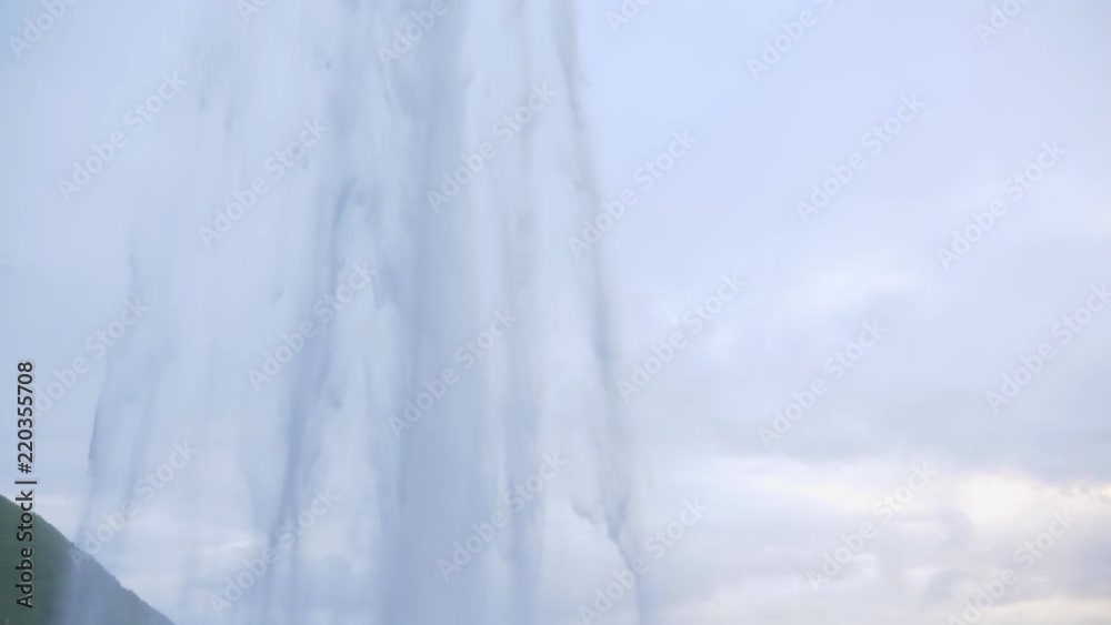 Slow pan down from behind majestic waterfall in Iceland Slow pan down from behind majestic waterfall in Iceland