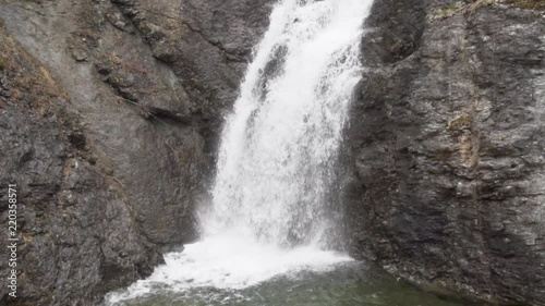 Medium waterfall falling with a u shaped stone brown wall on the background_slomo photo