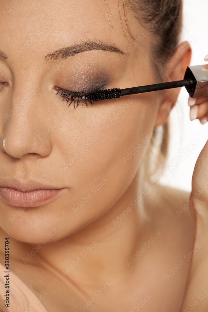 Closeup of young woman applying mascara