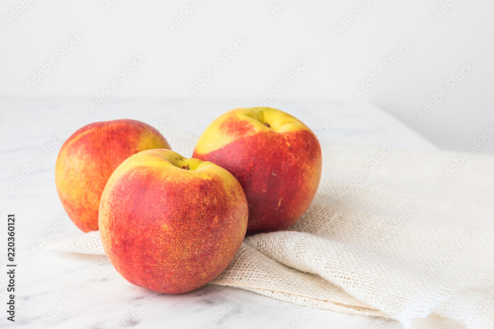 Three nectarines on a white marble background Three nectarines on a white marble background