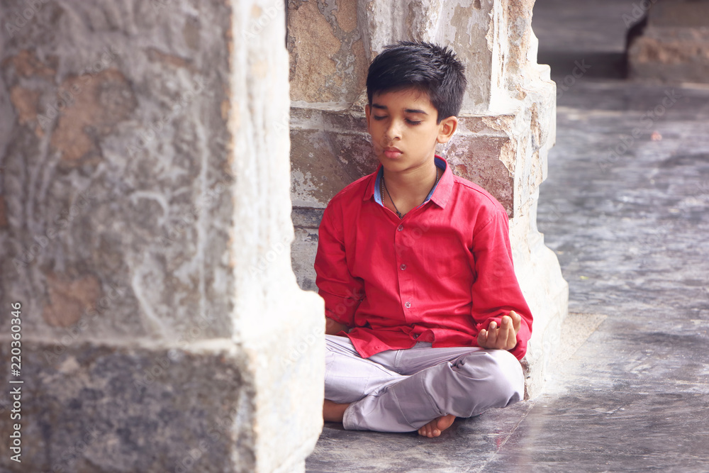 Indian young boy meditating at hindu temple Indian young boy meditating at hindu temple