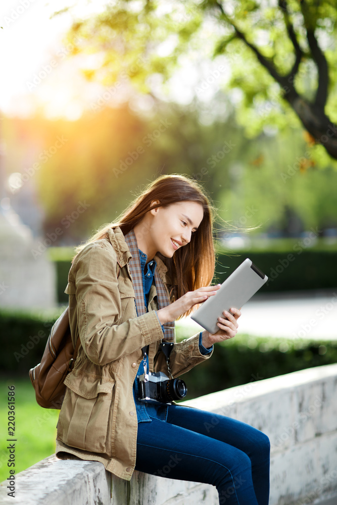 Young woman in casual clothes text messaging on the tablet at the sunset. Young woman in casual clothes text messaging on the tablet at the sunset.