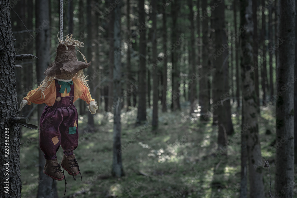 Scarecrow hanged with a rope in a dark forest