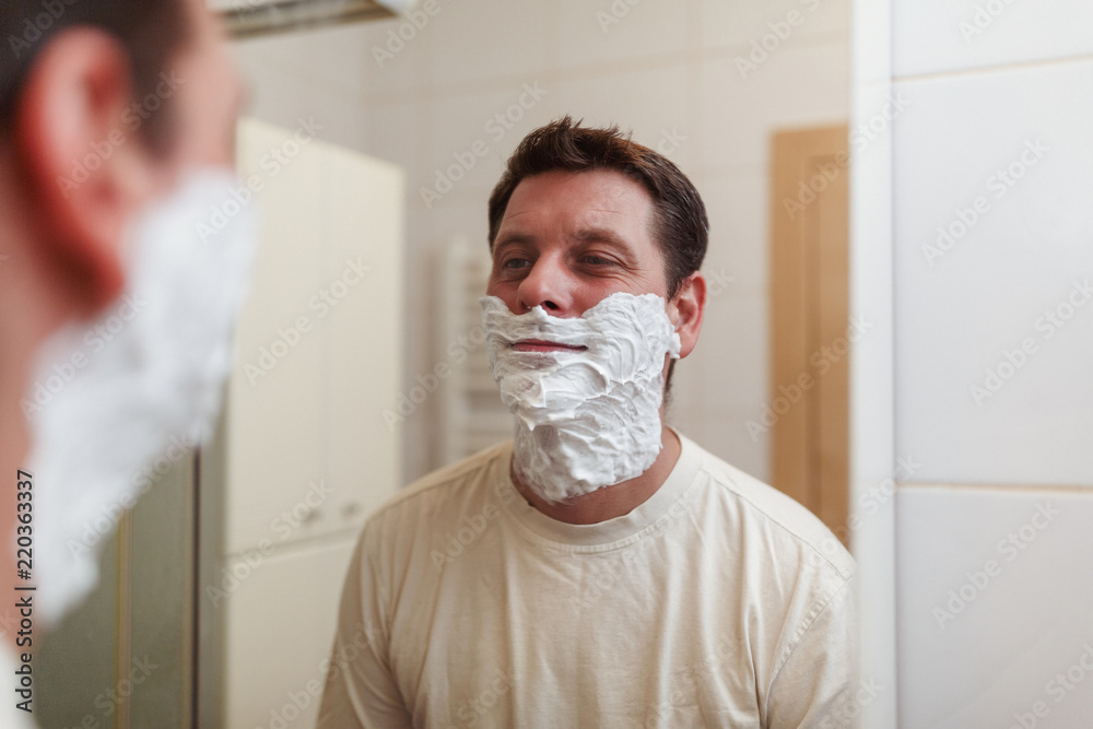 portrait of a handsome man with shaving foam on his face.