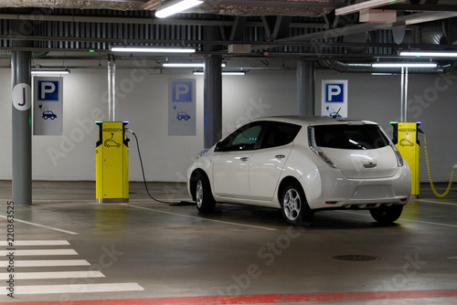 Fototapeta Naklejka Na Ścianę i Meble -  Electric car is charged at the charging station in the underground parking lot