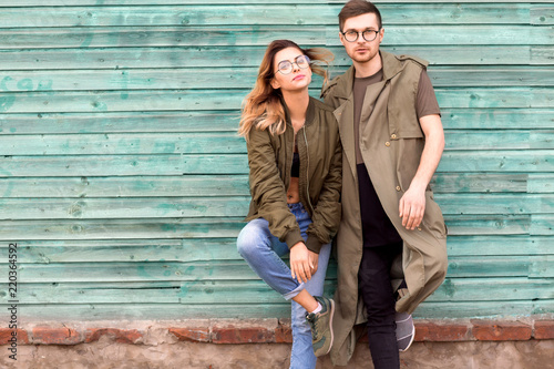 fashion couple standing posing near green wooden wall