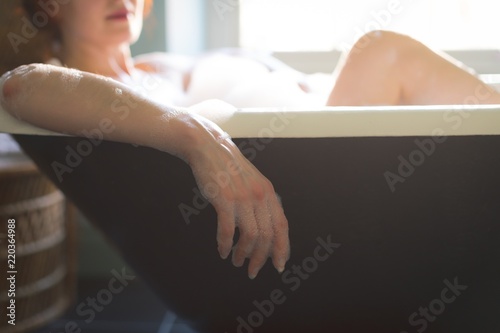 Woman taking bath in bathtub photo