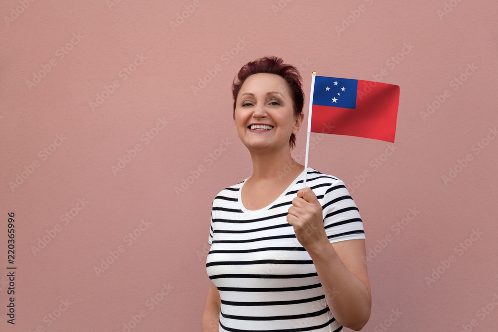 Samoa flag. Woman holding Samoa flag. Nice portrait of middle aged lady 40 50 years old with a national flag over pink wall background outdoors. Samoa flag. Woman holding Samoa flag. Nice portrait of middle aged lady 40 50 years old with a national flag over pink wall background outdoors.