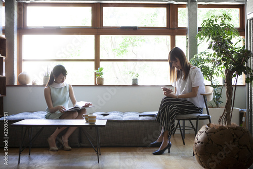 綺麗なオフィスで読書とスマホを見ている女性社員たち photo