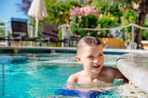 Happy boy child playing in pool, summer vacations