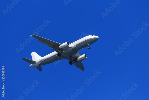 A white airplane flying in clear pale blue sky.