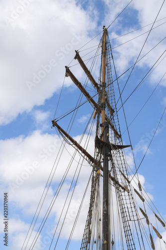masts and rigging of a historic sailing ship against the cloudy sky, travel and voyage concept with copy space, vertical