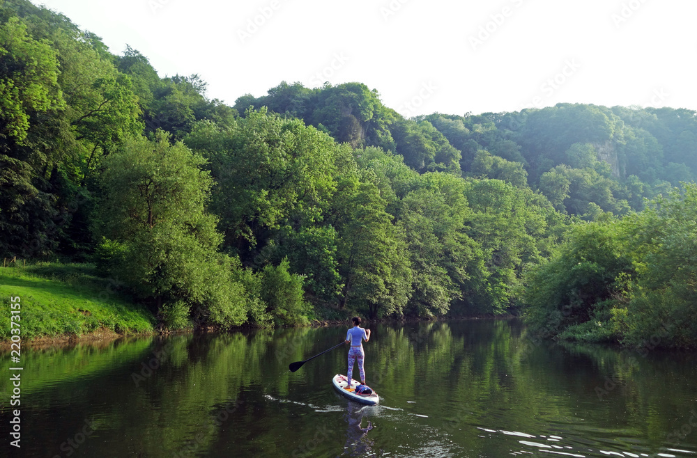 Paddle boarder deep in the Wye Valley Gorge, River Wye, Monmouthshire, Wales Paddle boarder deep in the Wye Valley Gorge, River Wye, Monmouthshire, Wales