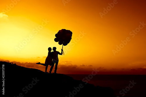 A loving couple is holding balls against the sunset