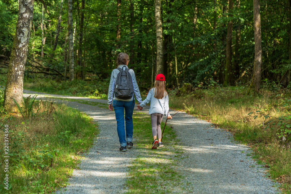 Fototapeta premium Mamma och barn vandrar på gusväg i skogen