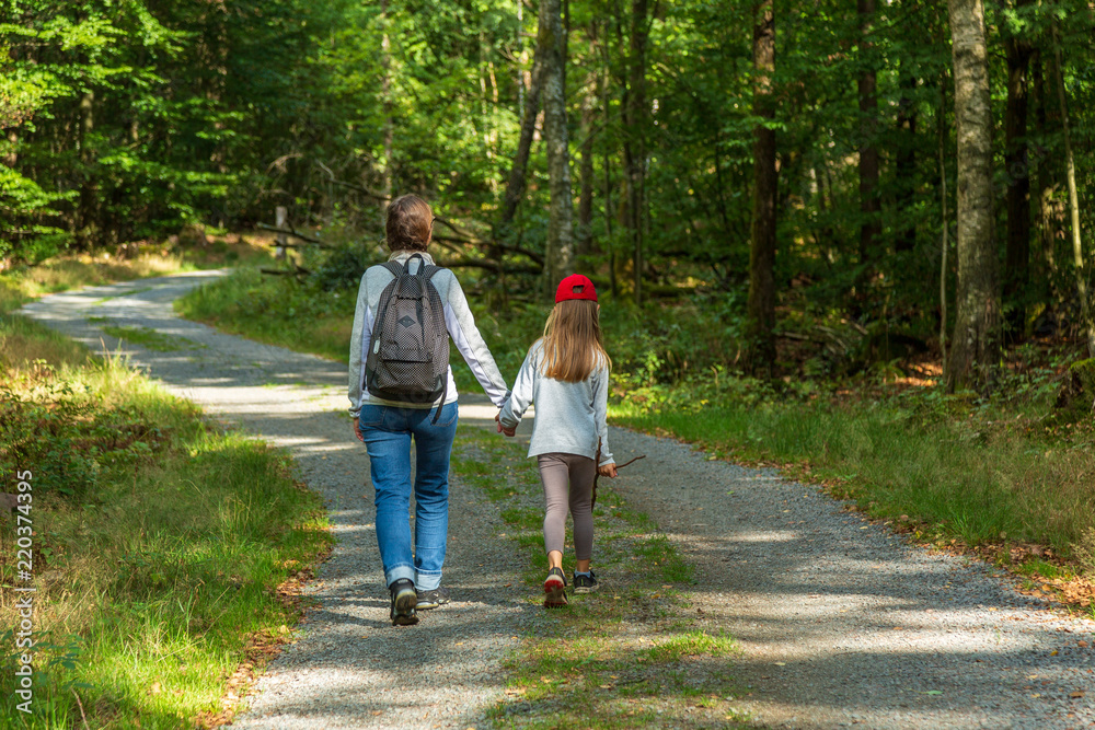 Fototapeta premium Mamma och barn vandrar på gusväg i skogen