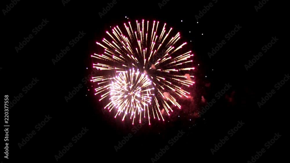 Bright fireworks on the holiday. In the night sky shines a bright fireball crimson. An interesting ball is in the center of fireworks, around small balls of different colors.